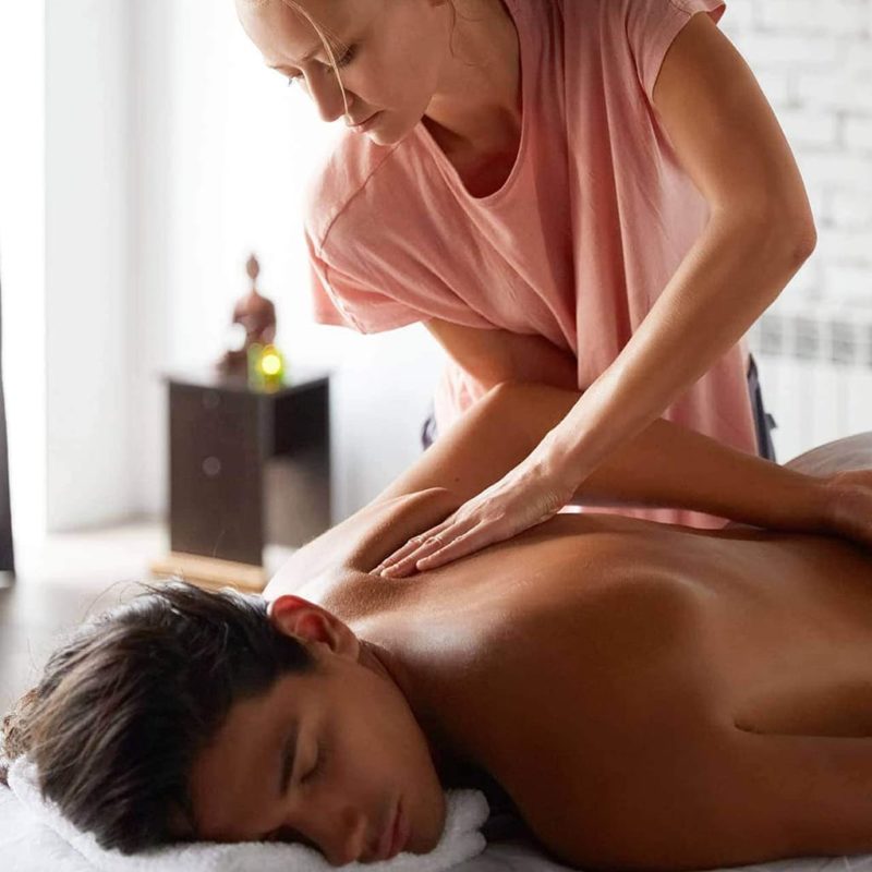 Massage therapist giving massage to young man